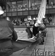 23.05.1968, Warszawa, Polska.
Ćwiczenia strażackie w Powszechnym Domu Towarowym Praga - strażacy przeprowadzają ewakuację osób znajdujących się w budynku. Widoczne są witryny sklepowe oraz fragment napisu: 