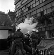 23.05.1968, Warszawa, Polska.
Ćwiczenia strażackie w Powszechnym Domu Towarowym Praga. Ewakuacja osób znajdujących się w budynku - strażacy pomagają kobiecie w ewakuacji. Na drugim planie widoczny jest fragment napisu: 