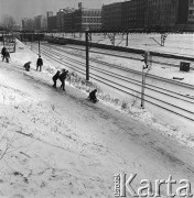 02.01.1968, Warszawa, Polska.
Okolice dworca kolejowego Warszawa Ochota. Dzieci zjeżdżające na sankach po nasypie kolejowym. W oddali widoczny jest przejeżdżający pociąg oraz zabudowa Alej Jerozolimskich.
Fot. Jarosław Tarań, zbiory Ośrodka KARTA