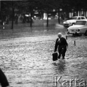 25.08.1968, Warszawa, Polska.
Ulewa w Śródmieściu Warszawy. Starsza kobieta brnąca przez zalaną ulicę.
Fot. Jarosław Tarań, zbiory Ośrodka KARTA