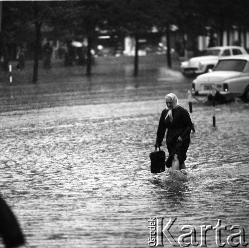 25.08.1968, Warszawa, Polska.
Ulewa w Śródmieściu Warszawy. Starsza kobieta brnąca przez zalaną ulicę.
Fot. Jarosław Tarań, zbiory Ośrodka KARTA