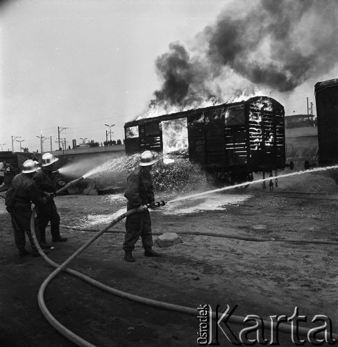 Październik 1968, Warszawa, Polska. 
Ćwiczenia samoobrony na Dworcu Wschodnim. Strażacy gaszący pianą płonący wagon, w tle podróżni na peronie obserwujący akcję. 
Fot. Jarosław Tarań, zbiory Ośrodka KARTA