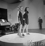 26.02.1968, Warszawa, Polska.
Pokaz setnej kolekcji firmy CORA zaprojektowanej przez Jadwigę Grabowską. Dwie modelki w chustach w kolorowe wzory i krótkich tunikach, w tle konferansjer.
Fot. Jarosław Tarań, zbiory Ośrodka KARTA