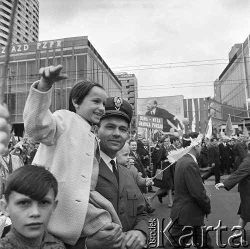 01.05.1968, Warszawa, Polska.
Pochód pierwszomajowy w centrum Warszawy. Milicjant z dziewczynką na ręku, w tle transparent z hasłem: 