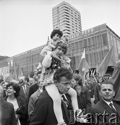 01.05.1968, Warszawa, Polska.
Pochód pierwszomajowy w centrum Warszawy. Na pierwszym planie mężczyzna trzymający na baranach dziewczynkę ubraną w strój ludowy, w tle Domy Towarowe 