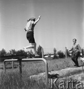 1968, Warszawa, Polska.
Harcerskie ćwiczenia obronne. Harcerka w skoku przez przeszkodę, w tle instruktor.
Fot. Jarosław Tarań, zbiory Ośrodka KARTA