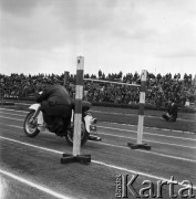 1968, Nowa Iwiczna, woj. Warszawa, Polska.
Szkoła Podoficerska MO Służby Ruchu Drogowego, pokaz jazdy akrobatycznej na motocyklu. W tle fotoreporter i widzowie zebrani na trybunach.
Fot. Jarosław Tarań, zbiory Ośrodka KARTA