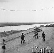 1968, Pińczów, woj. Kielce, Polska.
Widok na rzekę Nidę w Pińczowie. Na pierwszym planie dzieci jeżdzące na rowerach nad rzeką.
Fot. Jarosław Tarań, zbiory Ośrodka KARTA