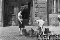 Czerwiec 1963, Warszawa, Polska.
Kobieta i dziewczynka zbierają z ulicy węgiel do wiader.
Fot. Jarosław Tarań, zbiory Ośrodka KARTA [63-33]

