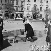 1968, Kraków, Polska.
Krakowska przekupka nalewająca wodę do wiadra na Rynku Głównym w Krakowie, w tle zabytkowe kamienice.
Fot. Jarosław Tarań, zbiory Ośrodka KARTA