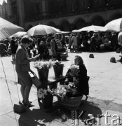 1968, Kraków, Polska.
Rynek Główny w Krakowie. Turystka kupująca kwiaty od krakowskiej handlarki, w tle tłum ludzi, stragany z kwiatami oraz Sukiennice.
Fot. Jarosław Tarań, zbiory Ośrodka KARTA