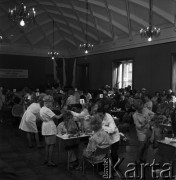Listopad 1968, Warszawa, Polska.
Stołeczny konkurs fryzjerski spółdzielczości pracy, ponumerowane stoły, przy których właśnie odbywa się tworzenie fryzur konkursowych, w tle flagi polskie i napis z nazwą konkursu. 
Fot. Jarosław Tarań, zbiory Ośrodka KARTA