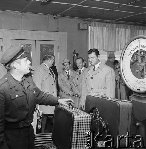 Wrzesień 1968, Warszawa, Polska.
Wyjazd polskich ciężarowców na Letnie Igrzyska Olimpijskie w Meksyku. W środku, uśmiechnięty, Waldemar Baszanowski. Ekipa wróciła z Maksyku z pięcioma medalami - jednym złotym (Waldemara Baszanowskiego) i czterema brązowymi (Henryka Trębickiego, Mariana Zielińskiego, Norberta Ozimka, Marka Gołębia). 
Odprawa bagaży.
Fot. Jarosław Tarań, zbiory Ośrodka KARTA