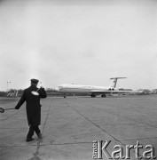 02.12.1968, Warszawa - Okęcie, Polska.
Samolot pasażerski produkcji radzieckiej Ił-62 na płycie lotniska. Na pierwszym planie kontroler ruchu naziemnego.
Fot. Jarosław Tarań, zbiory Ośrodka KARTA