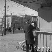 17.03.1963, Warszawa, Polska.
Mężczyzna w berecie pijący napój z butelki pod budką. 
Fot. Jarosław Tarań, zbiory Ośrodka KARTA [63-175]

