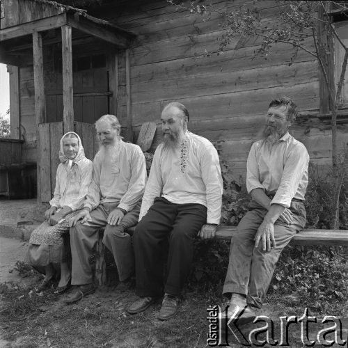 Lipiec 1963, Gabowe Grądy, Polska.
Wieś starowierców. Kobieta i trzej mężczyźni na ławce przed domem.
Fot. Jarosław Tarań, zbiory Ośrodka KARTA [63-199]

