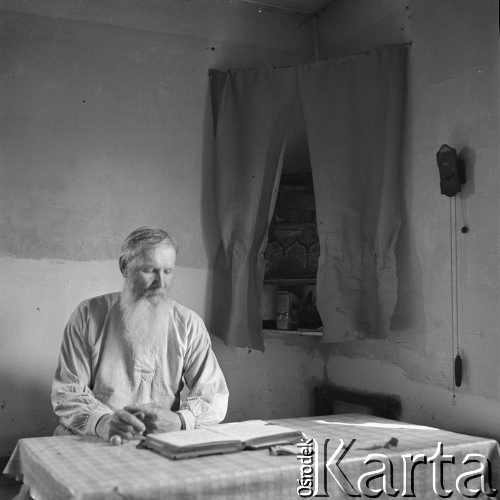 Lipiec 1963, Gabowe Grądy, Polska.
Wieś starowierców. Mężczyzna z brodą siedzący za stołem i czytający księgi.
Fot. Jarosław Tarań, zbiory Ośrodka KARTA [63-199]

