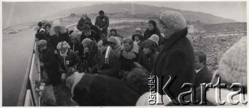 19.11.1984, Włocławek, Polska.
Śmierć ks. Jerzego Popiełuszki - modlitwa grupy wiernych z parafii pod wezwaniem Św. Stanisława Kostki w Warszawie przy tamie we Włocławku, miejscu śmierci ks. Jerzego Popiełuszki. Modlitwę prowadzi ks. Stanisław Małkowski (w środku kadru), po jego prawej stronie ojciec ks. Jerzego., z prawej strony kadru (częściowo załonięty - brat ks. Jerzego). Rozpoznani również: Danuta Rozworska, Leon Łochowski.
Fot. NN, zbiory Ośrodka KARTA
 
