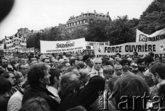 1981-1982, Paryż, Francja.
Manifestacja zorganizowana przez francuskie związki zawodowe na placu Inwalidów, obok ambasady PRL przy rue de Talleyrand. Wzięły w niej udział: Force Ouvriere, CFDT - Confédération Française Démocratique du Travail, CFTC - Confédération Française des Travailleurs Chrétiens, CGC- Confédération Erançaise de l'Encadrement oraz Union Nationale des Étudiants de France (UNEF). Na zdjęciu przemawiają Jean Meretik (z lewej), brat Garbriela Meretika i Sławomir Czarlewski. Manifestanci trzymają transparenty związku internowanych działaczy Solidarności, UNEF-u, Force Ouvriere, PCI.
Fot. Andrzej Mietkowski, zbiory Ośrodka KARTA