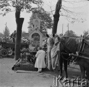 Lata 70., Warszawa, Polska.
Kobieta modląca się przy kapliczce. W tle targ przy pl. Politechniki.
Fot. Bogdan Łopieński, zbiory Ośrodka KARTA