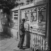 Początek czerwca 1961, Warszawa, Polska.
Mężczyzna naklejający plakaty na tablicy ogłoszeń.
Fot. Bogdan Łopieński, zbiory Ośrodka KARTA
