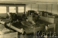 1941, Dorsten, III Rzesza Niemiecka.
Obóz jeniecki oficerów Wojska Polskiego. Wnętrze baraku drugiego, sali trzeciej: numerowane prycze i bagaże osobiste. Sale miały swoich dyżurnych wyznaczanych spośród współjeńców, do ich obowiązków należało m.in. dbanie o czystość pomieszczeń, schludność żołnierzy, przynoszenie kotłów z posiłkami do baraków, pilnowanie ciszy nocnej.
Fot. zbiory Ośrodka KARTA, Pogotowie Archiwalne [PA_024], przekazali Dorota i Tomasz Wojciechowscy