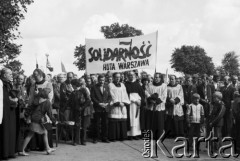 30.08.1981, Westerplatte, Polska.
Uroczystość poświęcenia krzyża ponownie ustawionego nad grobami poległych - delegacja hutników warszawskich. W pierwszym rzędzie stoją, od lewej strony: Danuta Wałęsa (bokiem), Lech Wałęsa, NN, NN, ksiądz Henryk Jankowski, NN, ksiądz Jerzy Popiełuszko i Jacek Lipiński. Napis na transparencie: 