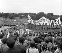 16-23.06.1983, Warszawa, Polska.
Druga pielgrzymka Jana Pawła II do Polski. Wierni - z uniesionymi do góry dłońmi złożonymi w znak zwycięstwa. Na pierwszym planie - transparent Konfederacji Polski Niepodległej, w oddali widoczny jest przejeżdżający kondukt papieski.
Fot. Adam Szymański, zbiory Ośrodka KARTA, kolekcję zdjęć przekazał Adam Szymański