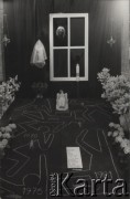 Lata 80., Polska.
Alegoryczne przedstawienie Wielkanocnego Grobu Pańskiego - wokół rzeźby Ukrzyżowanego Chrystusa narysowane zostały kredą kontury ludzkich ciał oraz roczne daty: 1956, 1968, 1970, 1976, 1981. Na drugim planie - paląca się świeca oraz obraz Matki Boskiej Częstochowskiej widoczny w okiennicy.   
Fot. NN, zbiory Ośrodka KARTA