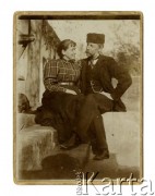 Ok. 1900, brak miejsca.
Mężczyzna w czapce i kobieta w bluzce w kratę i ciemnej spódnicy siedzący przed budynkiem.
Fot. NN, zbiory Ośrodka KARTA, Pogotowie Archiwalne [PAF_002], udostępnił Kazimierz Dorant