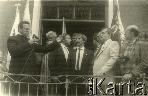 Sierpień 1987, Gdańsk, Polska.
Wiec na dziedzińcu przed budynkiem parafialnym kościoła pw. św. Brygidy w związku z 7. rocznicą strajków w sierpniu 1980 roku; na schodach plebanii przemawia ksiądz Henryk Jankowski, w jasnym ganiturze stoi Lech Wałęsa, za nim Szymon Pawlicki.
Fot. NN, Archiwum Federacji Młodzieży Walczącej, zbiory Ośrodka KARTA
