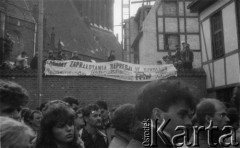 Koniec lat 80., Gdańsk, Polska.
Wiec na terenie kościoła św. Brygidy. Na murze przedstawiciele Federacji Młodzieży Walczącej z transparentem: 