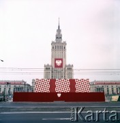 1.05.1974, Warszawa, Polska.
Obchody Święta Pracy. Pałac Kultury i Nauki z okolicznościowymi dekoracjami i godłem państwowym. Przed gmachem Pałacu, na placu Defilad ustawiona udekorowana trybuna. Widok od strony ulicy Marszałkowskiej.
Fot. Edward Grochowicz, zbiory Ośrodka KARTA.
