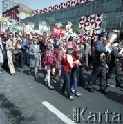 1.05.1974, Warszawa, Polska.
Obchody Święta Pracy. Uczestnicy pochodu zmierzają ulicą Marszałkowską. Na pierwszym planie członkowie orkiestry dętej oraz dzieci niosące czerwone flagi. 
Fot. Edward Grochowicz, zbiory Ośrodka KARTA.