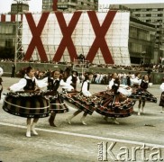 22.07.1974, Warszawa, Polska.
30. rocznica powstania Polskiej Rzeczpospolitej Ludowej. W pochodzie na Placu Defilad bierze udział delegacja z ludowego zespołu pieśni i tańca prawdopodobnie z Podhala. W głębi widoczny transparent ustawiony przed Domem Towarowym Wars, Sawa i Junior.
Fot. Edward Grochowicz, zbiory Ośrodka KARTA