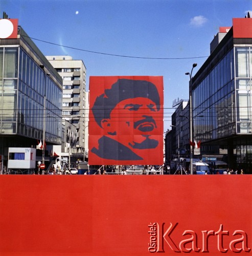 1.05.1975, Warszawa, Polska.
Obchody Święta Pracy. Dekoracja okolicznościowa ustawiona między budynkami Domów Towarowych Centrum - transparent z wizerunkiem Włodzimierza Lenina. Widok od ulicy Marszałkowskiej.
Fot. Edward Grochowicz, zbiory Ośrodka KARTA.
