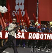 1.05.1975, Warszawa, Polska.
Obchody Święta Pracy. Uczestnicy pochodu niosą czerwone sztandary, dekoracje w postaci sztucznych kwiatów oraz transparenty z hasłami propagandowymi. 
Fot. Edward Grochowicz, zbiory Ośrodka KARTA.
