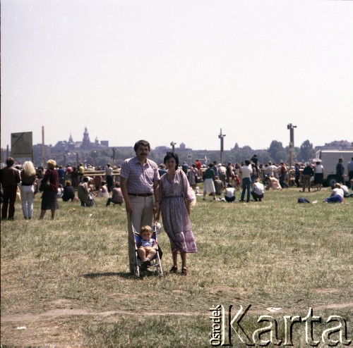 22.06.1983, Kraków, Polska.
Druga pielgrzymka papieża Jana Pawła II do Polski w dniach 16-23 czerwca 1983 roku. Małżeństwo z dzieckiem podczas mszy świętej sprawowanej przez Ojca Świętego na Błoniach Krakowskich.
Fot. Edward Grochowicz, zbiory Ośrodka KARTA