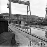 Około 1966, Gdańsk, Polska.
Stocznia Gdańska (od 15.04.1967 Stocznia Gdańska im. Lenina). Fotoreporter ustawia kadr przy jednej z pochylni. W tle suwnica oraz budynki stoczniowe.
Fot. Edward Grochowicz, zbiory Ośrodka KARTA.