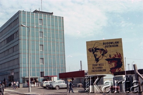 1985, Dąbrowa Górnicza, Polska.  
Przed bramą wjazdową na teren kombinatu metalurgicznego „Huta Katowice”. Po lewej stronie budynek zarządu przedsiębiorstwa, po prawej widoczny transparent z hasłem: ”Budowlani-Hutnikom. Zróbmy więcej niż to wynika z naszych obowiązków”. 
Fot. Edward Grochowicz, zbiory Ośrodka KARTA.