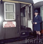 Lata 70. lub 80., Polska.
Fotografia reklamowa dla Centralnego Biura Obsługi Podróżnych PKP POLRES. Pracownica PKP przy wejściu do stojącego na peronie ekspresu 