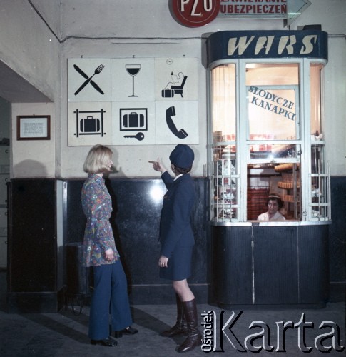 Lata 70. lub 80., Polska.
Fotografia reklamowa dla Centralnego Biura Obsługi Podróżnych PKP POLRES. Pracownica PKP na dworcu kolejowym zapoznaje podróżną z ofertą przedsiębiorstwa.
Fot. Edward Grochowicz, zbiory Ośrodka KARTA.
