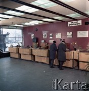 Lata 70. lub 80., Polska.
Fotografia reklamowa dla Centralnego Biura Obsługi Podróżnych PKP POLRES - klienci przy stanowiskach sprzedaży biletów w biurze POLRESU.
Fot. Edward Grochowicz, zbiory Ośrodka KARTA.
