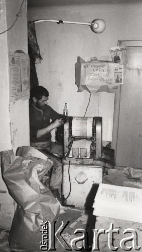 Lata 80., Polska.
Podziemna drukarnia. Na ścianie napis: 