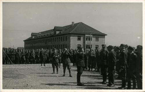 Ok. 6.05.1945, Murnau am Staffelsee, Bawaria, III Rzesza Niemiecka.
Naczelny Wódz Polskich Sił Zbrojnych gen. Tadeusz Bór-Komorowski (w pierwszym rzędzie 4. z prawej) podczas wizyty w Oflagu Murnau VII A. Na przeciwko niego stoi gen. Juliusz Rómmel (salutuje).
Fot. NN, kolekcja Marcina Rudzińskiego, zbiory Ośrodka KARTA