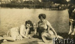 Lata 20., Rzeczpospolita Polska.
Elżbieta Zajączkowska, matka Larysy (z prawej) odpoczywa nad stawem w towarzystwie przyjaciół. Z lewej prawdopodobnie ciotka Agata Kamieńska z domu Michelson (ciotka Elżbiety). Z prawej strony stoi Larysa Zajączkowska.  
Fot. NN, kolekcja Larysy Zajączkowskiej-Mitznerowej, zbiory Ośrodka KARTA