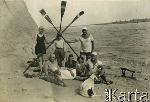 Lata 20., Rzeczpospolita Polska.
Grupa osób odpoczywająca na plaży nad jeziorem.
Fot. NN, kolekcja Larysy Zajączkowskiej-Mitznerowej, zbiory Ośrodka KARTA