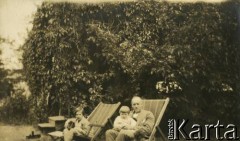 Ok. 1929, Olszanka, woj. warszawskie, Rzeczpospolita Polska.
Larysa Zajączkowska (z lewej) siedzi na leżaku przed domem letniskowym, wynajmowanym w Puszczy Mariańskiej. Obok niej ojciec Piotr, trzymając na kolanach jej brata Jerzego. 
Fot. NN, kolekcja Larysy Zajączkowskiej-Mitznerowej, zbiory Ośrodka KARTA