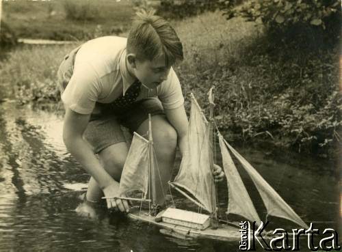 Lato 1939, Moszczenica, woj. łódzkie, Rzeczpospolita Polska.
Jerzy Zajączkowski (brat Larysy) puszcza drewniany statek na rzece.
Fot. NN, kolekcja Larysy Zajączkowskiej-Mitznerowej, zbiory Ośrodka KARTA