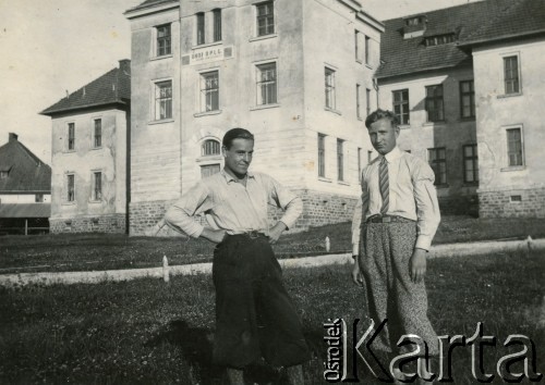 Lata 30., Buczacz, Polska.
Stefan Szymula (1. z lewej) - przed wojną pracował w Powiatowym Zarządzie Drogowym w Buczaczu. Po wrześniu 1939 ukrywał się. Aresztowany po nieudanej ucieczce do Rumunii, osadzony w więzieniu w Czortkowie, później w Starobielsku. Skazany na 5 lat obozu, zesłany w styczniu 1941 roku na Syberię. Dostał się do Armii Andersa, z którą został ewakuowany do Iranu. Przeszedł z nią cały szlak bliskowschodni. W Palestynie ukończył Szkołę Podchorążych Piechoty Rezerwy i został mianowany porucznikiem. Walczył pod Monte Cassino, w dniu zakończenia wojny ożenił się z Włoszką Silvią Valli. W 1948 roku emigrował do Argentyny. Na zdjęciu z kolegą przy budynku Obozu Obrony Przeciwlotniczej i Gazowej.
Fot. NN, zbiory Silvii Szymuli, reprodukcje cyfrowe w  Bibliotece Polskiej im. Ignacego Domeyki w Buenos Aires (Biblioteca Polaca Ignacio Domeyko) i w Ośrodku KARTA w Warszawie